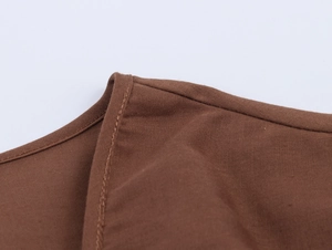 Vue macro de la texture en coton marron et des détails de couture sur la robe ethnique col V