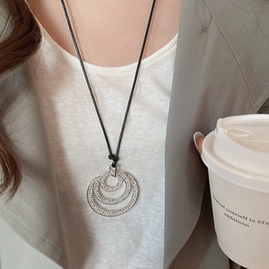 Detail shot of multi-layer sparkling crystal circle pendants on a black cord necklace