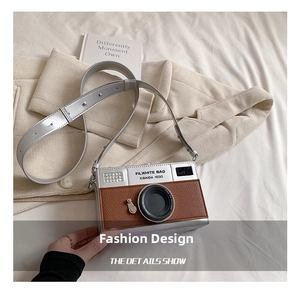 Detail of creative vintage camera bag in brown lychee leather with silver metal accents