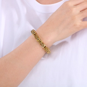 Gros plan d'un bracelet byzantin en acier inoxydable doré porté sur un poignet masculin