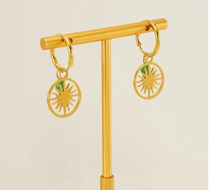 Macro detail of gold sunburst drop earrings featuring an emerald green center stone