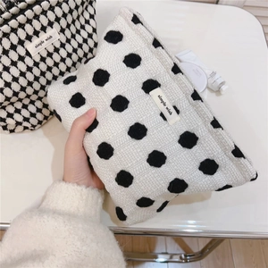 Détail de trousses de maquillage en tricot à carreaux et pois avec étiquette brodée