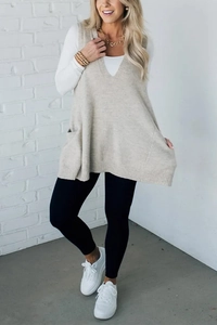 Detail view of beige V-neck knitted vest showing soft texture and side pocket detail