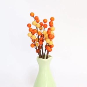 Detail of artificial orange and yellow berries in a green vase for harvest decor