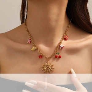 Détail du collier en acier doré avec pendentifs colorés en forme de soleil et de cerise