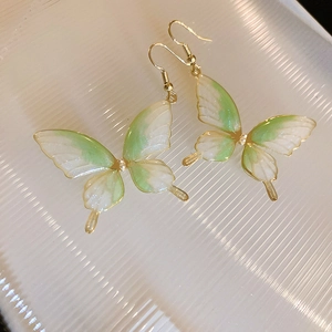 Détail des boucles d'oreilles papillon avec dégradé vert et perles en métal doré