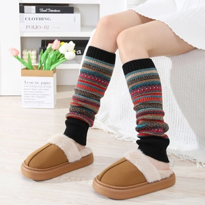 Détail de jambières en tricot rayé coloré portées avec des pantoufles en peluche marron