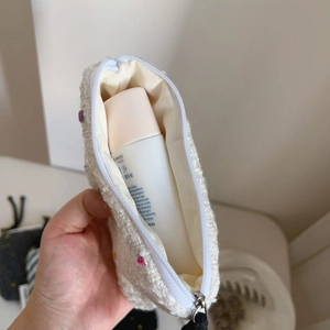 Dettaglio della borsa cosmetica in peluche ricamata che mostra lo spazio interno e l'apertura