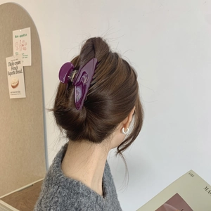 Detail of purple acetate hair claw clip with gold lettering in a French style hairstyle