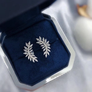 Macro shot of leaf-shaped silver earrings with sparkling zircon stones in a velvet box