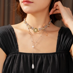 Close-up of layered necklace featuring a starburst pearl pendant and amber crystal detail