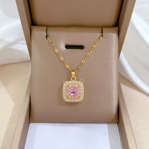 Macro shot of gold-plated square pendant with pink crystals in a brown jewelry box