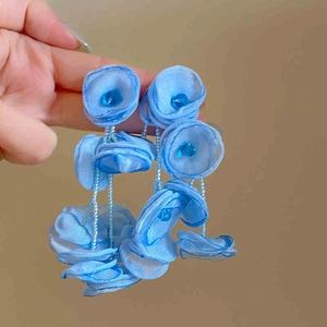 Detail of long blue tulle flower tassel earrings with beaded accents for a vacation look