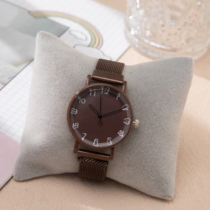Gros plan d'une montre à quartz marron sur coussin avec arrière-plan artistique