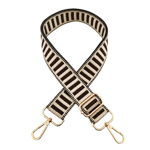 Detailed close-up of adjustable striped bag strap with premium gold metal hardware