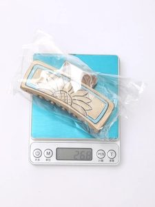 Detailed view of a beige western floral hair claw clip in packaging on a digital scale