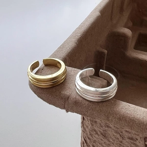 Macro shot of minimalist gold and silver S925 rings with triple layered groove texture