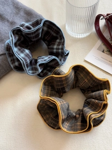 Close-up of blue and brown plaid scrunchies with thick wool texture and fine edge stitching