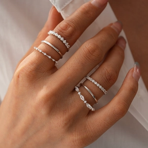 Set of six minimalist zircon rings in silver finish worn as stylish layered hand jewelry
