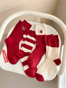 Detail showing red cashmere mid-tube socks with premium embroidery and stripe patterns