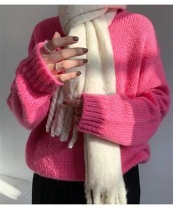 Close-up of soft beige cashmere-like scarf texture with chunky tassels and pink knit