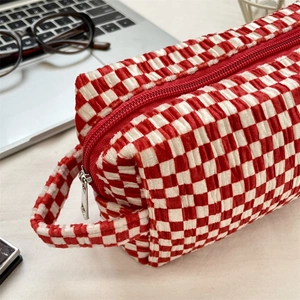 Detail of red and white checkered velvet makeup bag with texture and silver zipper