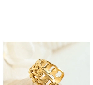 Macro shot of an elegant gold-plated hollow-out ring on soft white fabric background
