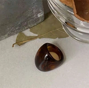 Amber acrylic resin ring with vintage geometric design on a textured stone surface