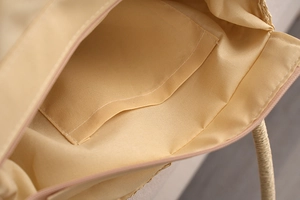 Close-up of beige woven straw bag interior showing fabric lining and zipper pocket detail