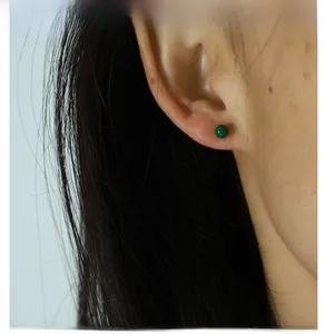 Close-up of a minimalist green malachite stud earring worn on the earlobe