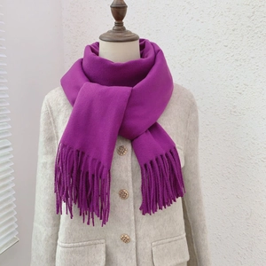 Detail of purple faux cashmere scarf with tassels styled on a model in a beige coat