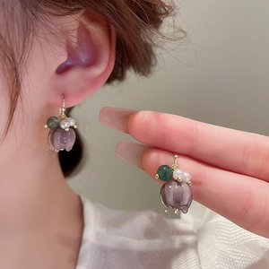 Detail of purple fabric flower earrings with white pearls and gold metal hooks