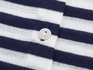 Macro view of blue and white striped knit fabric with a glossy pearl button detail