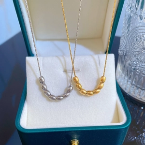 Titanium steel necklaces in gold and silver finish with oval bead pendants on jewelry box