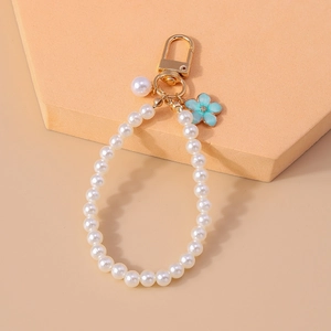 Detail of beaded pearl keychain featuring blue flower charm and golden lobster clasp