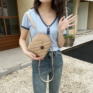 Quilted khaki PU leather backpack with a cute cat pendant and adjustable straps on a model
