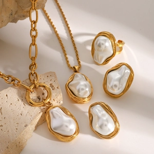 Baroque pearl jewelry set with gold necklaces, earrings, and ring on stone background