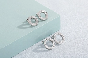 Detail of silver stainless steel stud earrings with cubic zirconia on blue pedestals