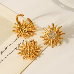 Macro detail of sun-shaped gold ring and stud earrings with crystal on calligraphy card