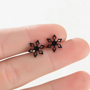 Macro shot of minimalist black snowflake earrings in stainless steel on fingers