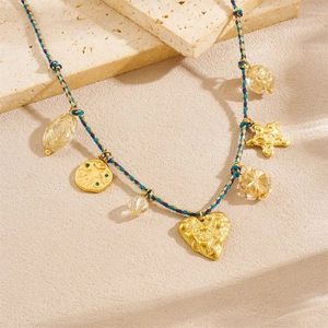 Bohemian hand-woven rope necklace with gold heart and starfish pendants on stone surface