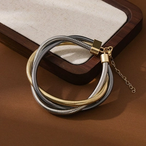 Detailed view of layered gold and silver spring collar bracelet with extension chain