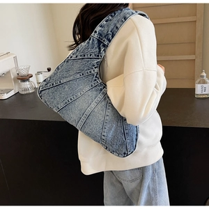 Détail du sac à bandoulière en denim bleu montrant la fermeture éclair et les coutures