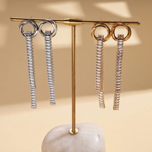 Elegant gold and silver tassel earrings with zircons displayed on a metal jewelry stand