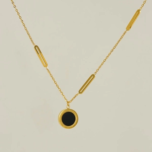 Detail of a minimalist gold necklace with double-sided black and white round pendant