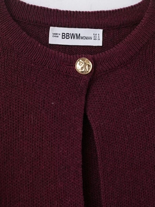Detail of burgundy knit cardigan neckline with vintage gold button and white woven label