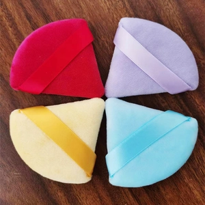 Detailed view of colorful triangular velvet makeup puffs on dark wooden background