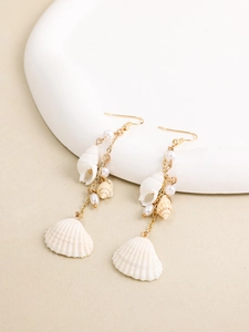 Detail of bohemian drop earrings with white shells and pearls on gold chains