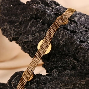Macro shot of 18K gold plated woven mesh bracelet with round turquoise plate on volcanic stone