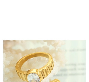 Close-up of golden stainless steel ring with vertical textures and oval zircon center